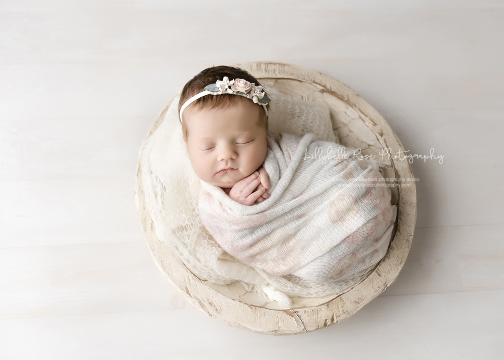 sleepy newborn in bowl prop with cream and pink