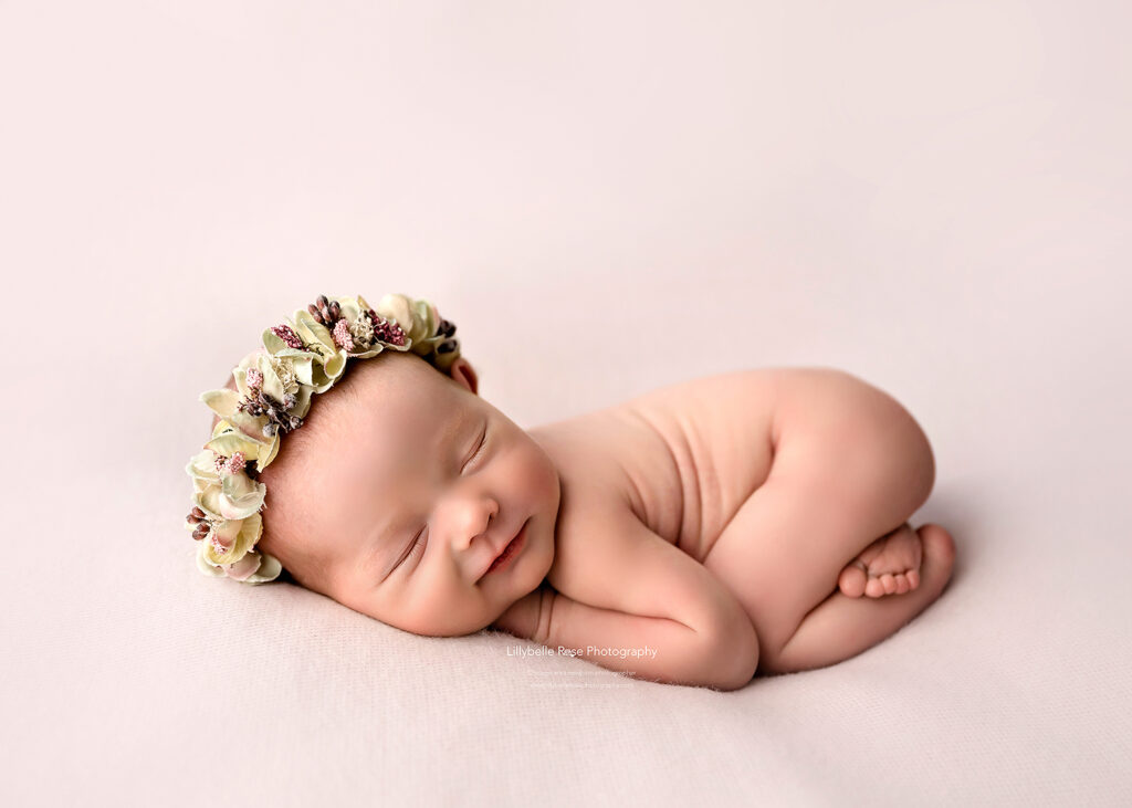 smiling baby on pink blanket with floral headband Chicago baby stores