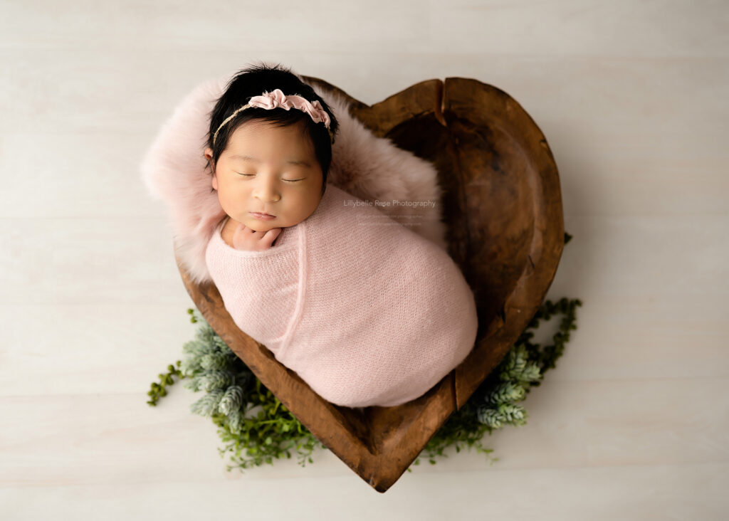 baby girl in heart prop with pink wrap
