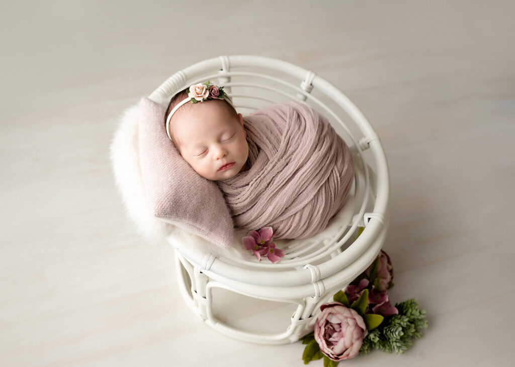 baby girl swaddled in a papason prop chair