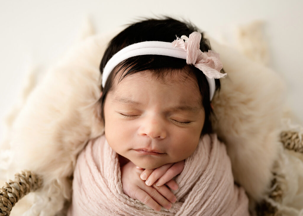 new born baby girl wrapped in pink with bow