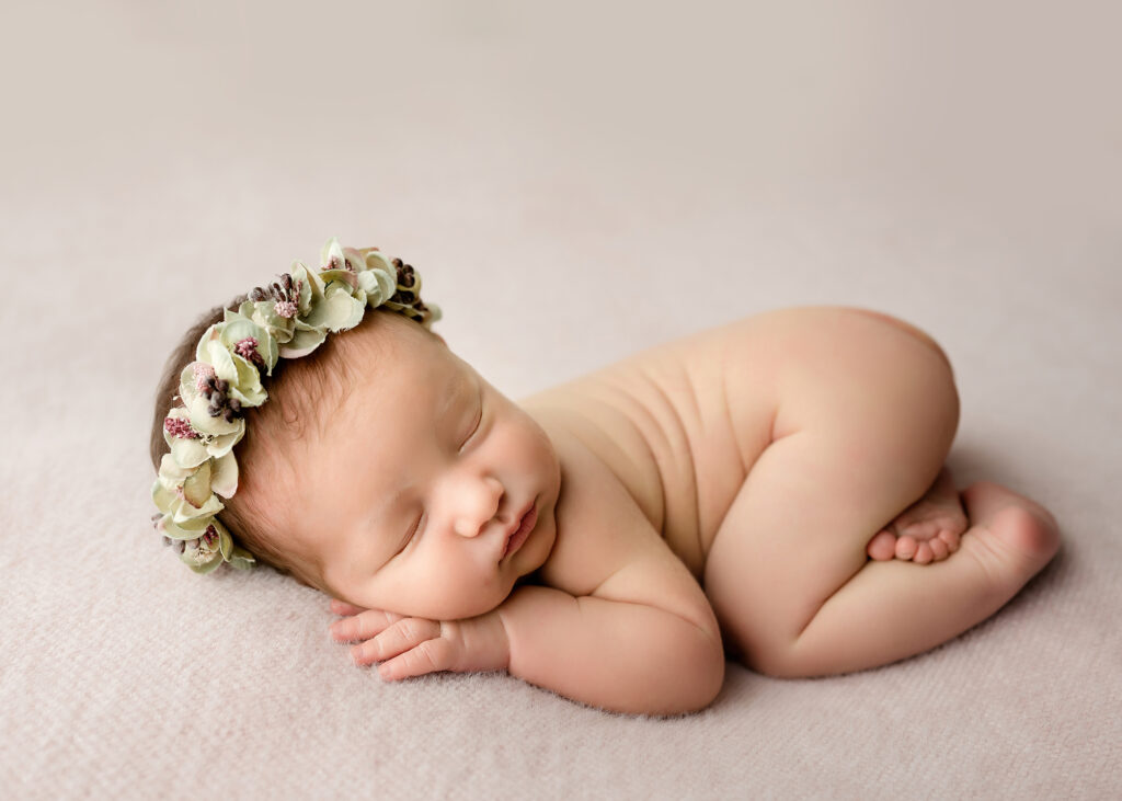 Pretty newborn with a floral halo on pink fuzzy fabric