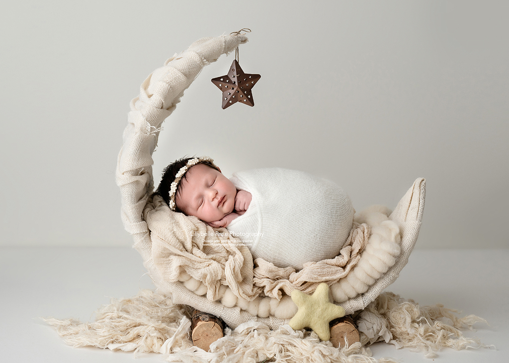 Cute newborn with cream moon prop and textured layers