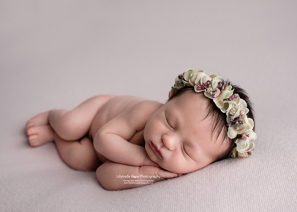 Beautiful baby girl sleeping on pink with dried floral halo
