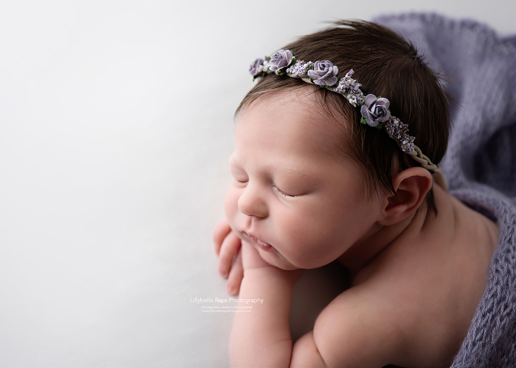 Newborn profile of cute baby girl with purple headband and swaddle