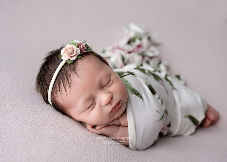 newborn baby girl wrapped in floral swaddle with matching headband