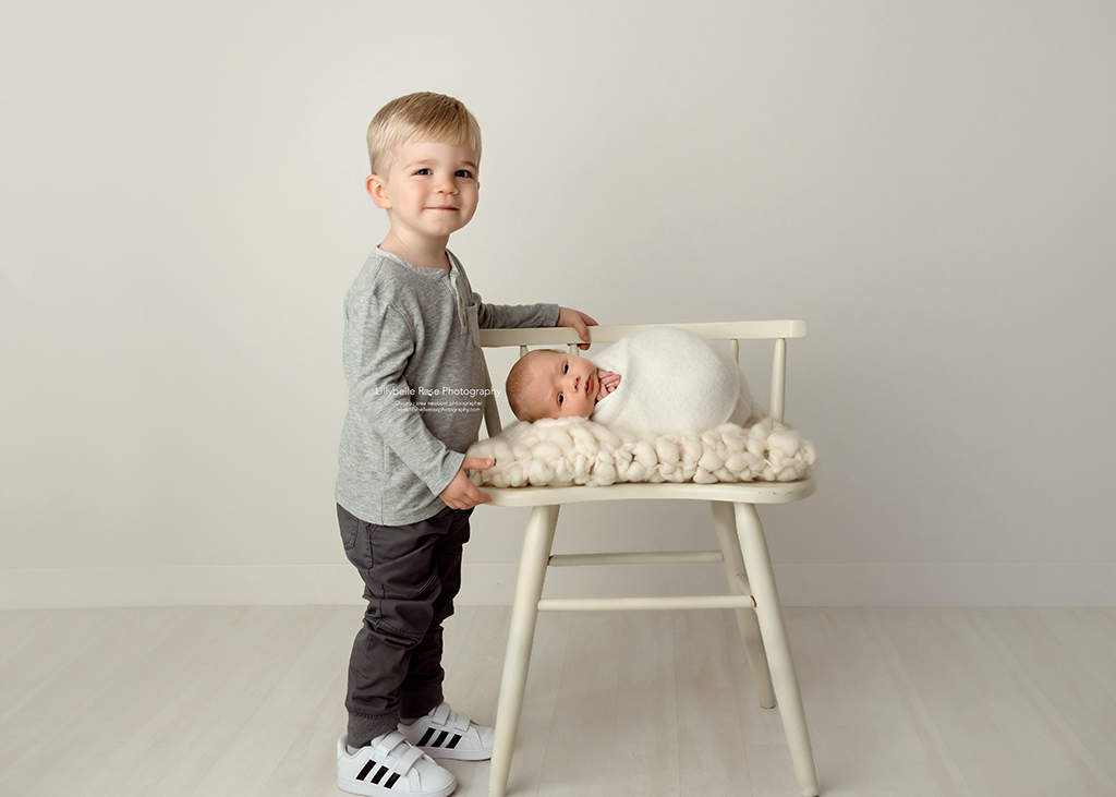 Baby brother being held by big brother in a photo studio