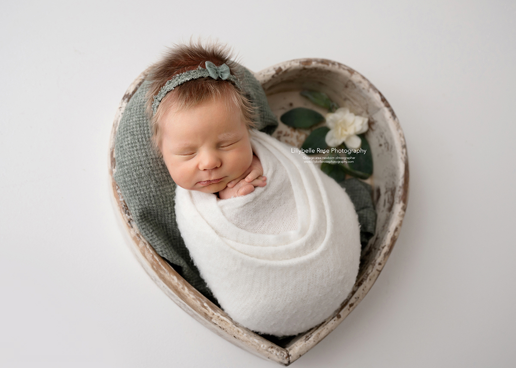 baby newborn girl with adorable hair in heart prop