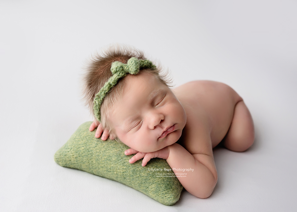 Chunky newborn cheeks on pretty newborn sleeping on green pillow prop