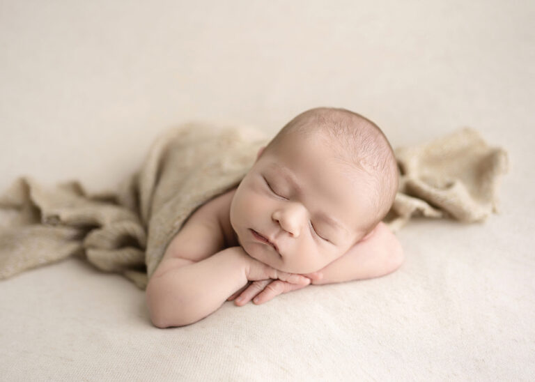 Newborn Photographer, a baby sleeps peacefully with a little blanket snuggled for warmth.