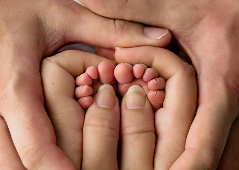 Newborn Photographer, a mother's hand holds her new baby's little feet.