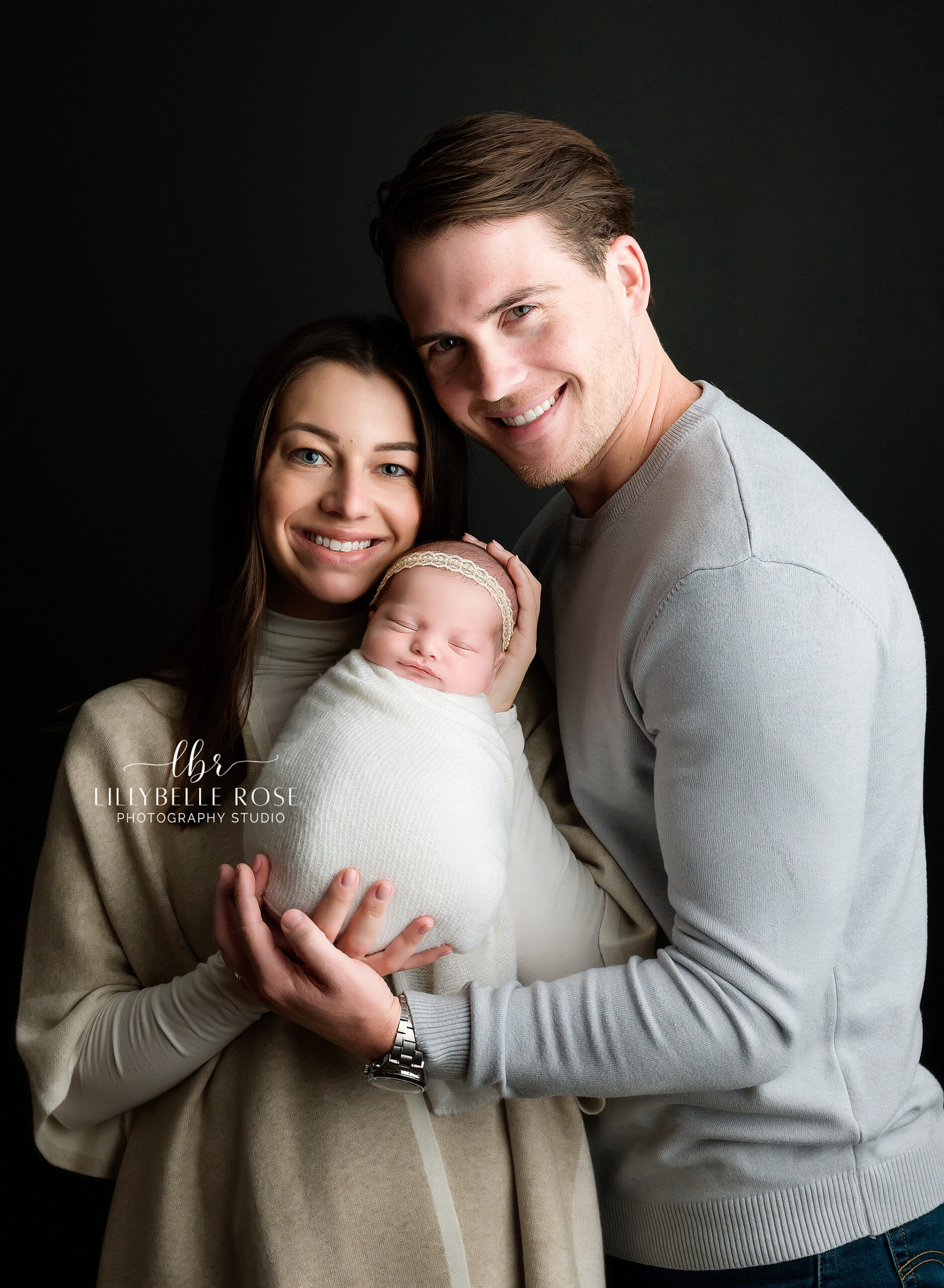 Newborn Photographer, a mother and father snuggle close as mom holds their new baby